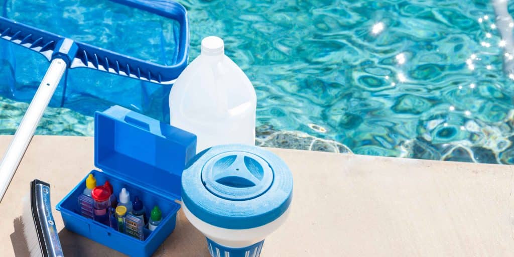 Professional pool cleaning tools and chemicals including skimmer, brush, test kit, and chlorine dispenser by PureWave Pools in Santa Cruz